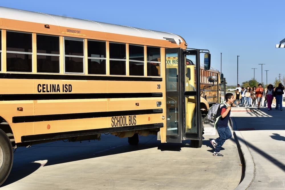 a student walk away from a yellow school bus