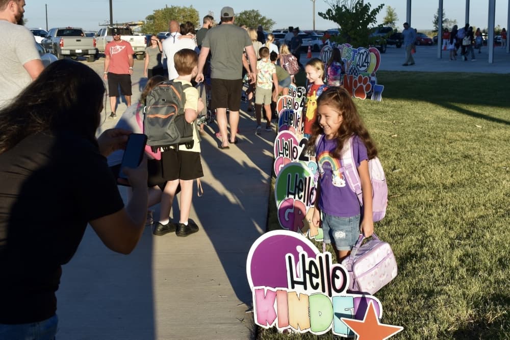 a young girl poses by a Hello Kindergarten sign