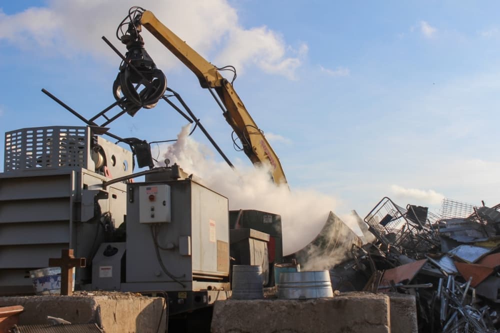 Comal Iron & Metals uses a crane to place metals into their bailer. These metals are then crushed into bales weighing anywhere between 800-1200 lbs. Once these bails arrive to the mill they are put through a giant shredder that separates the metal into nonferrous and ferrous metals before going into the smelter. (Photo by Amira Van Leeuwen/Community Impact)
