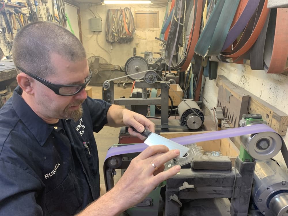 Montgomery sharpens a knife in the workspace attached to his showroom. (Shawn Arrajj/Community Impact)