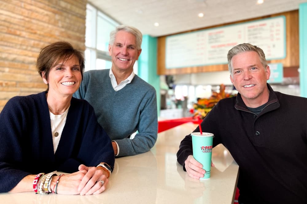 Three adults stand smiling in a fast food restaurant.