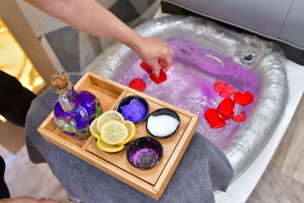 This image shows rose petals being placed in a pedicure spa bowl.