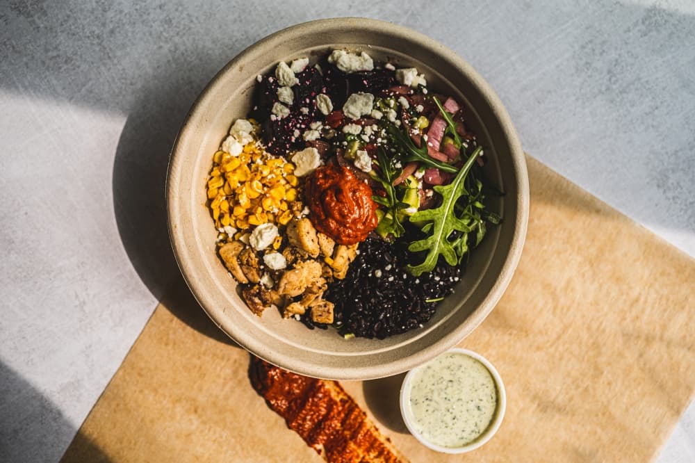 A Mediterranean Harissa signature bowl filled with healthy food is pictured on a table.