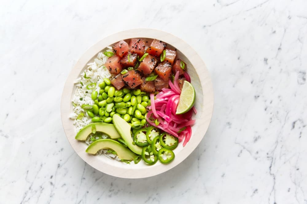 The Aloha Poke bowl filled with fresh food is pictured on a table.
