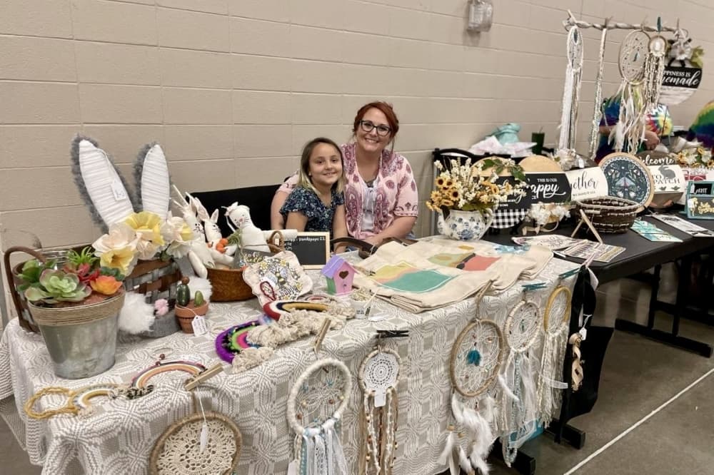 A photo of a Fall Craft Fair table with women and girl 