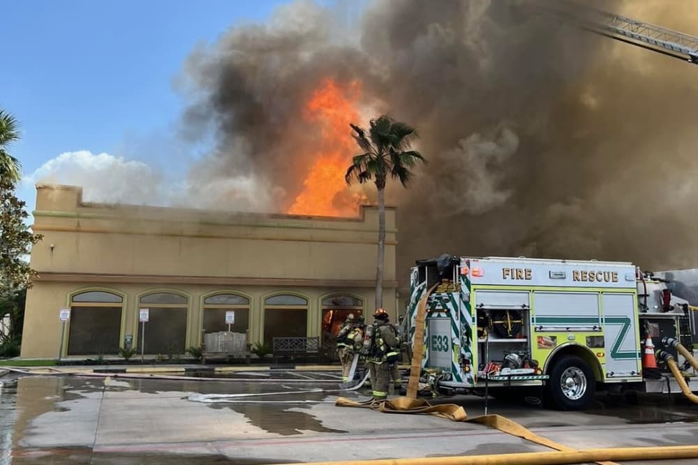 The photo shows the Los Cucos restaurant on fire and fire trucks next to it.