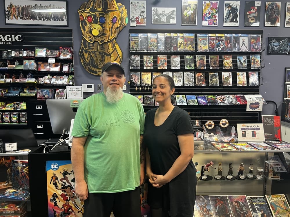 man in green shirt and woman in black standing in front of counter 