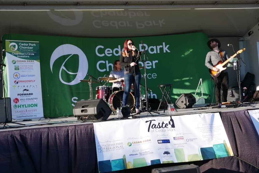 People perform live music on a stage outside.