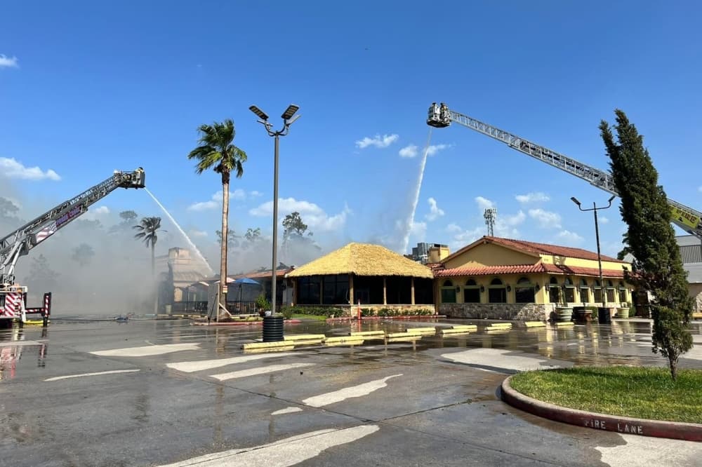 The photo shows the Los Cucos restaurant on fire and fire trucks next to it.