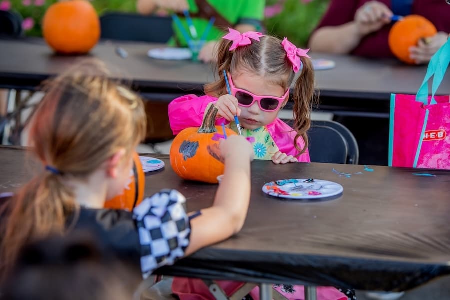 Two young girls paint a pumpkin.