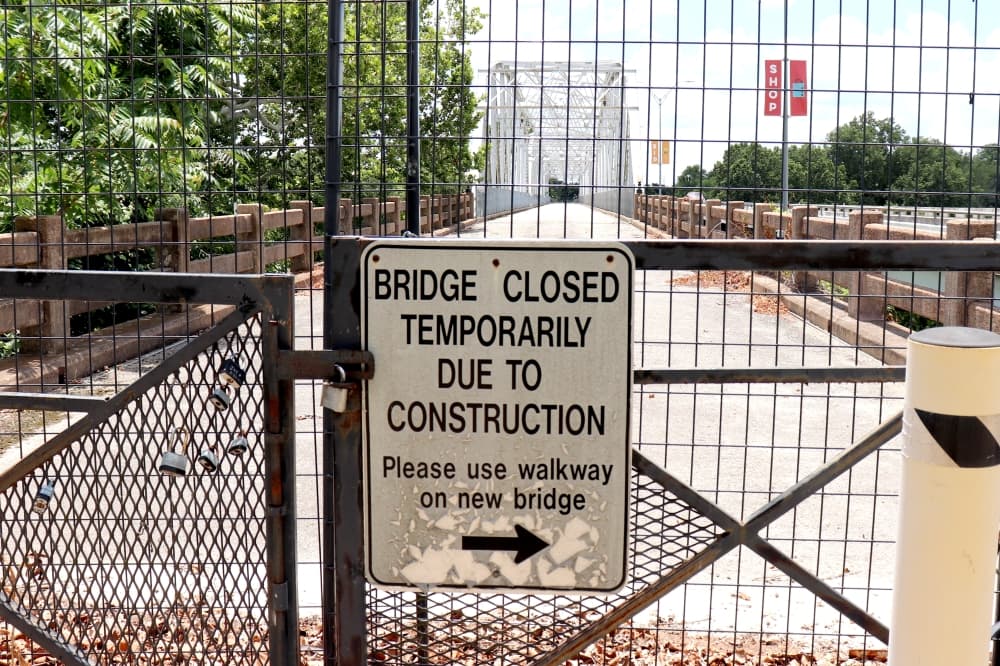 A closed sign on the gate of an old bridge.