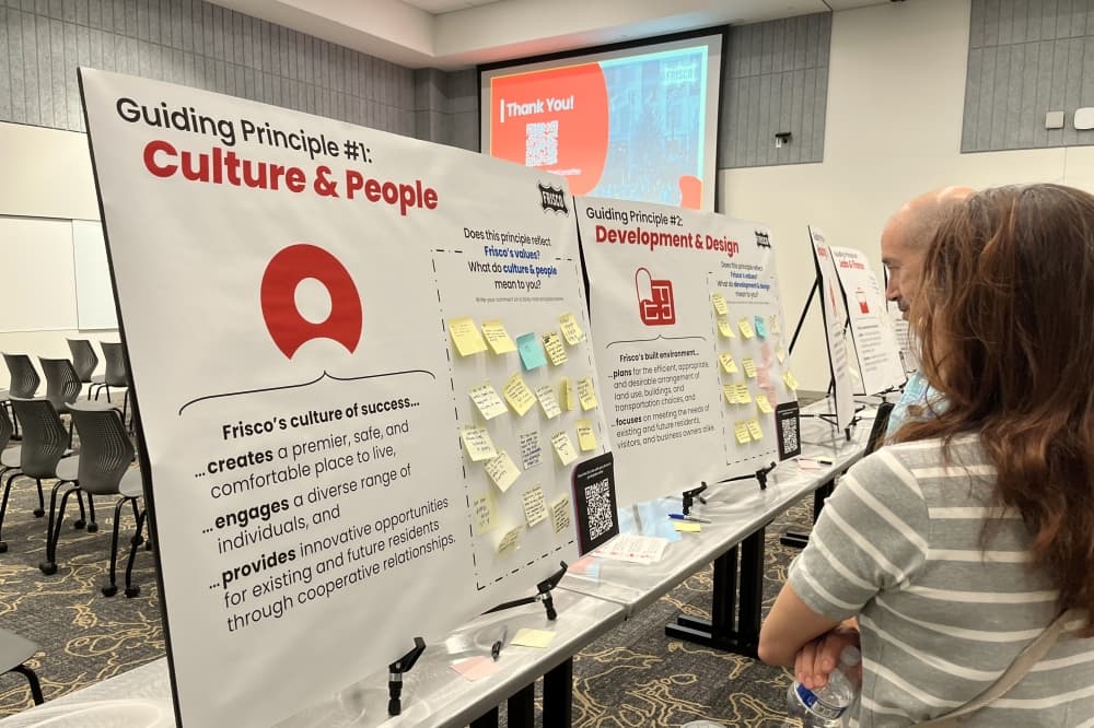 people gather around boards with information and sticky notes