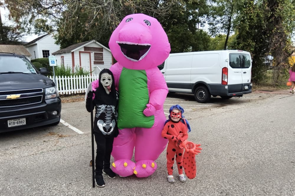 Children in Halloween costumes including Barney, a skeleton and super hero.