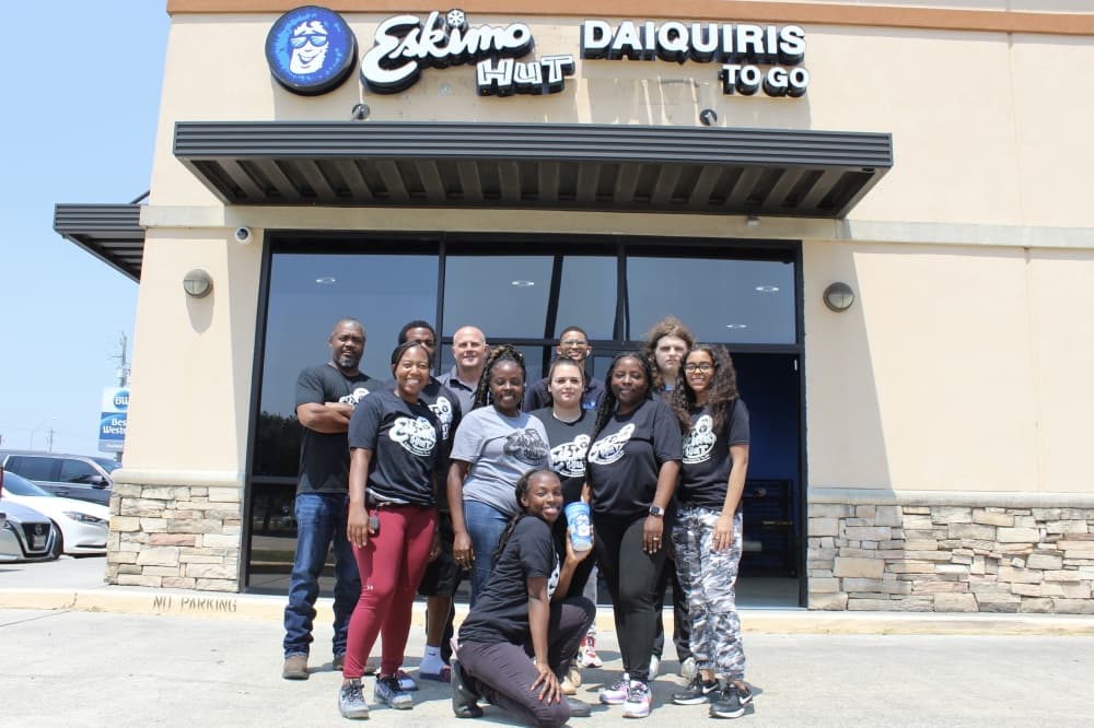 Staff and owners of Eskimo Hut in Pearland pose in front of the shop's front sign. (Rachel Leland/Community Impact)
