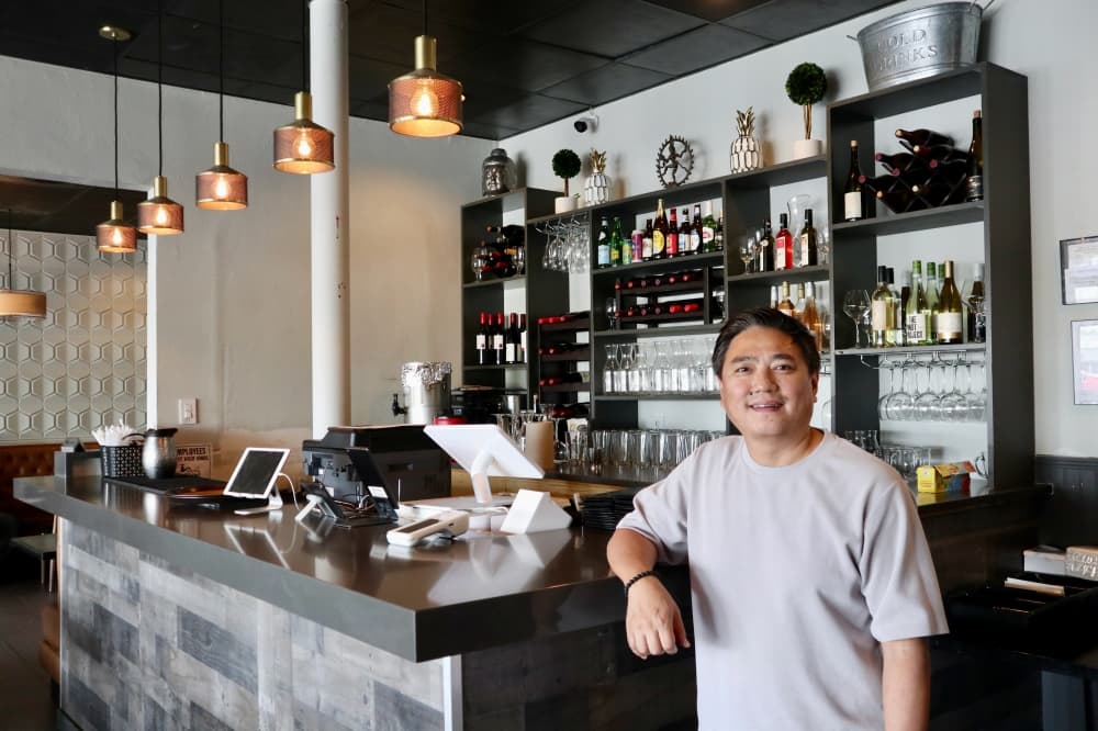 Co-owner Thiniso Tashi poses, smiling at the bar