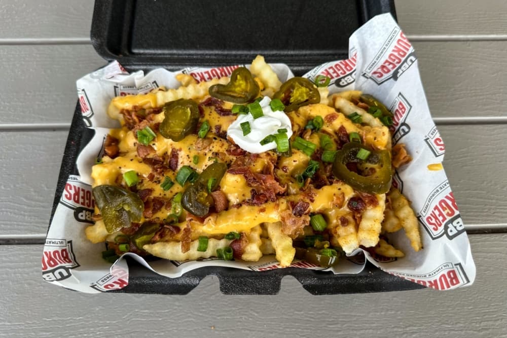 seasoned crinkle cut fries, signature queso, chopped grilled bacon, jalapenos, sour cream and green onions. (Amira Van Leeuwen/Community Impact)