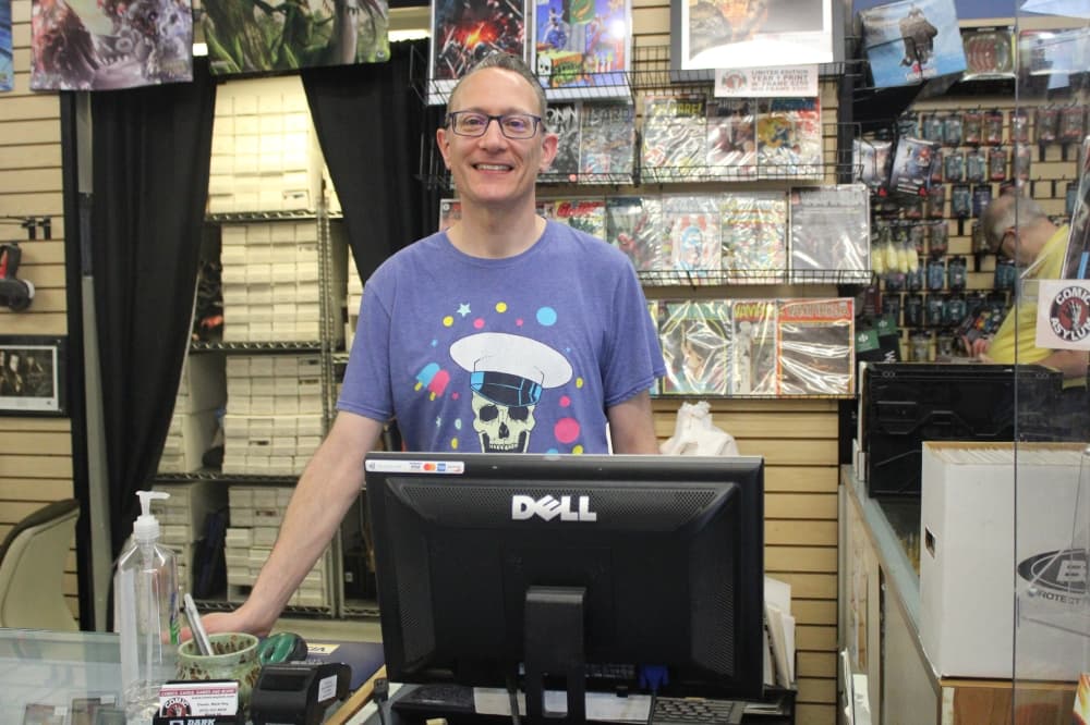 Mark Hay standing behind the counter of Comic Asylum