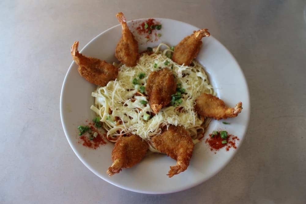 Gold Band Creole is seven butterflied jumbo shrimp that's rolled in seasoned breadcrumbs, deep fried and served over a bed of fettuccine pasta with a spicy creole sauce and Evangeline's cajun Aioli with a gold band of parmesan cheese. (Amira Van Leeuwen/Community Impact)