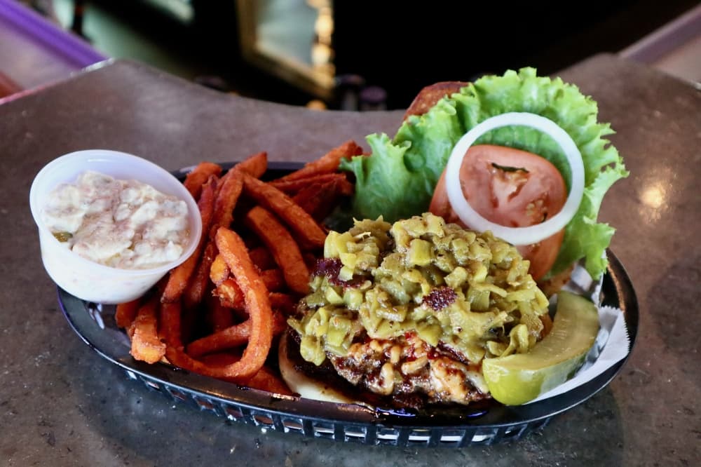 Slammer Burger with green chilies, pepper jack and avocado on top and a side of sweet potato fries.