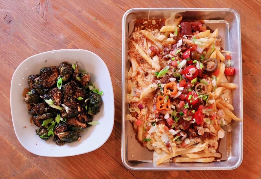 Crispy brussel sprouts tossed in sweet and spicy sauce (left). Loaded fries topped with queso, chili, pico, jalapeno ranch & green onions (right).