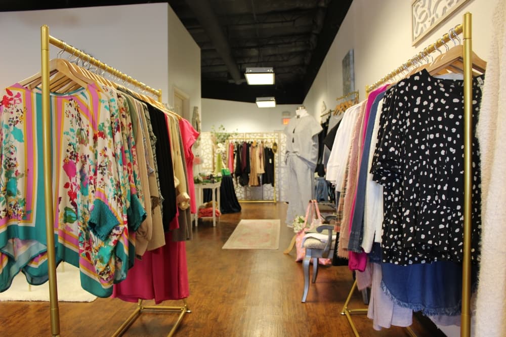 Clothes hang on two racks on either side of a hallway. 