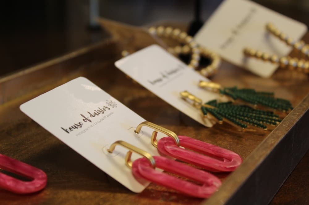 Two sets of earrings on display with the boutique's name House of Daisies.