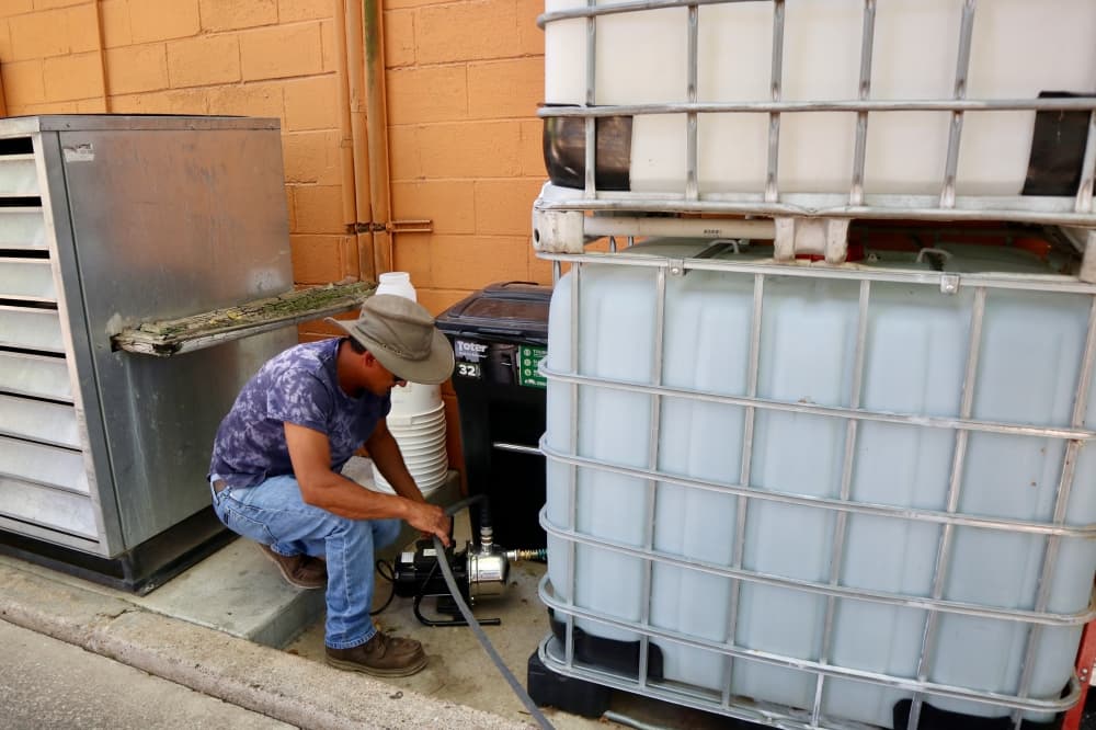 Fonda San Miguel property manager Diego Rodriguez connects the water tanks to the hose