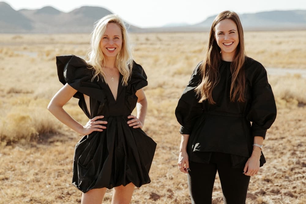 Sisters and co-founders of Miron Crosby, Lizzie Means Duplantis and Sarah Means pose together, clad in black.