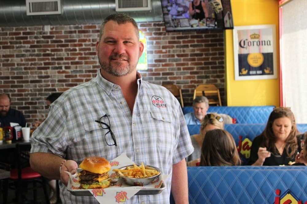 Jax Grill owner holding burger at Bellaire location