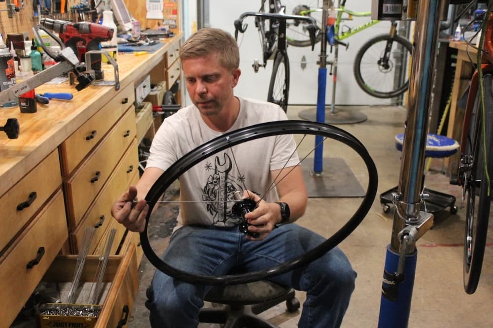 Howard building a bicycle wheel. (Amira Van Leeuwen/Community Impact)