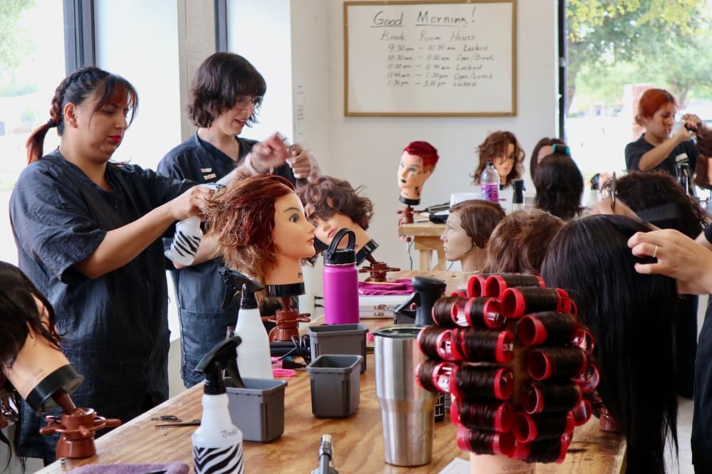 Students at CTBC in Round Rock practice cutting hair on mannequins