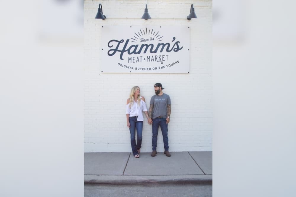 Photo of the Hesters under the Hamm's Meat and Market sign