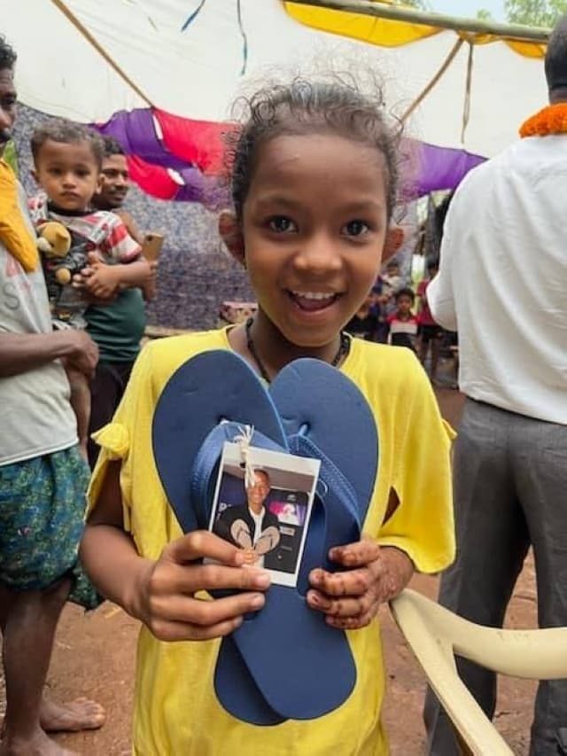 Young girl from India holds a pair of new flip-flops.