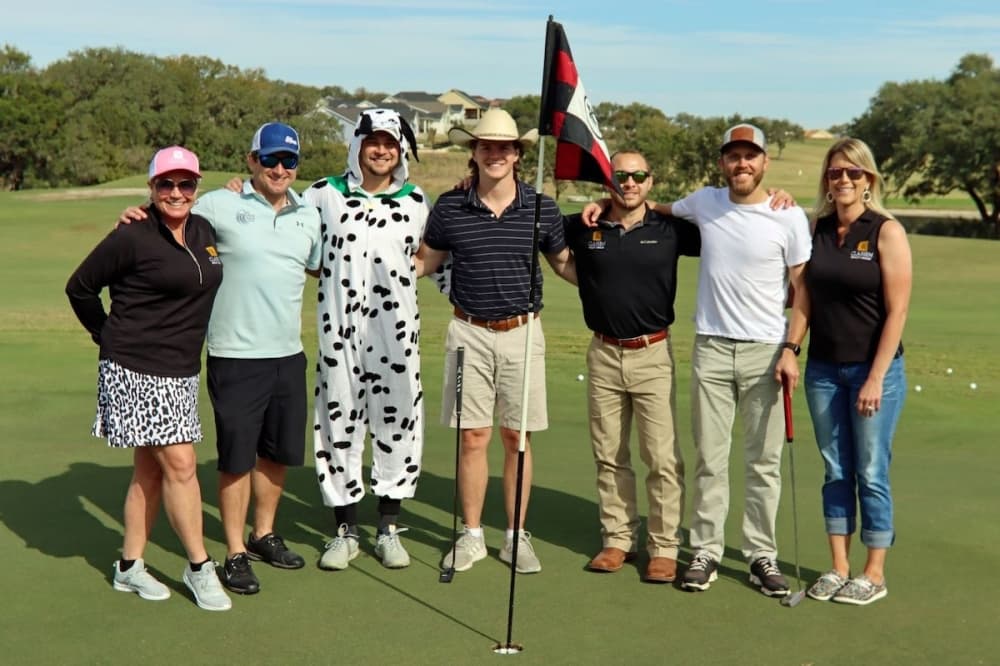 seven people pose for a photo on a golf course