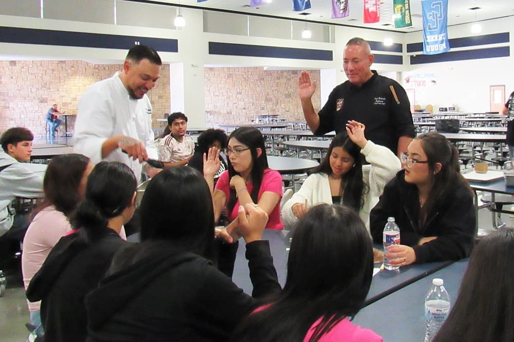 A chef speaks with students.