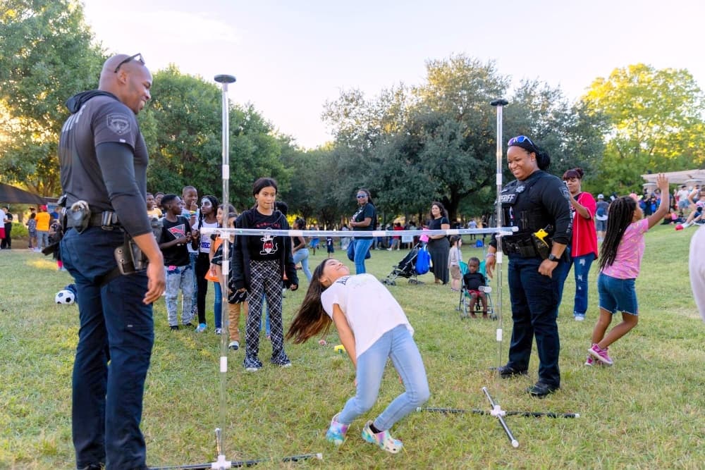 Kid playing limbo with officers.