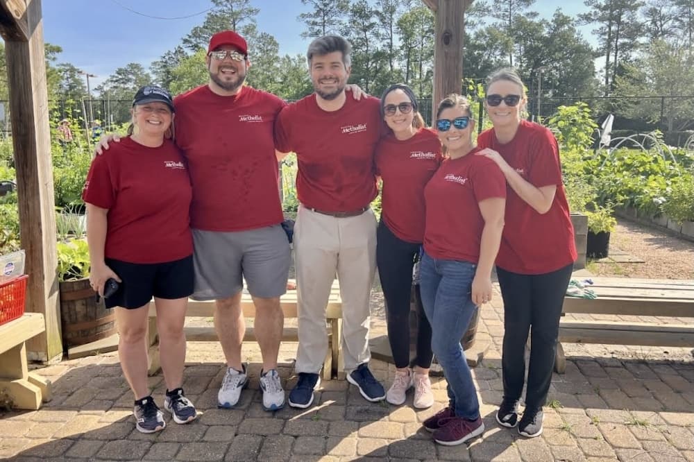 Employees of the Houston Methodist The Woodlands Hospital pose for a photo at Veggie Village during a harvest event. 