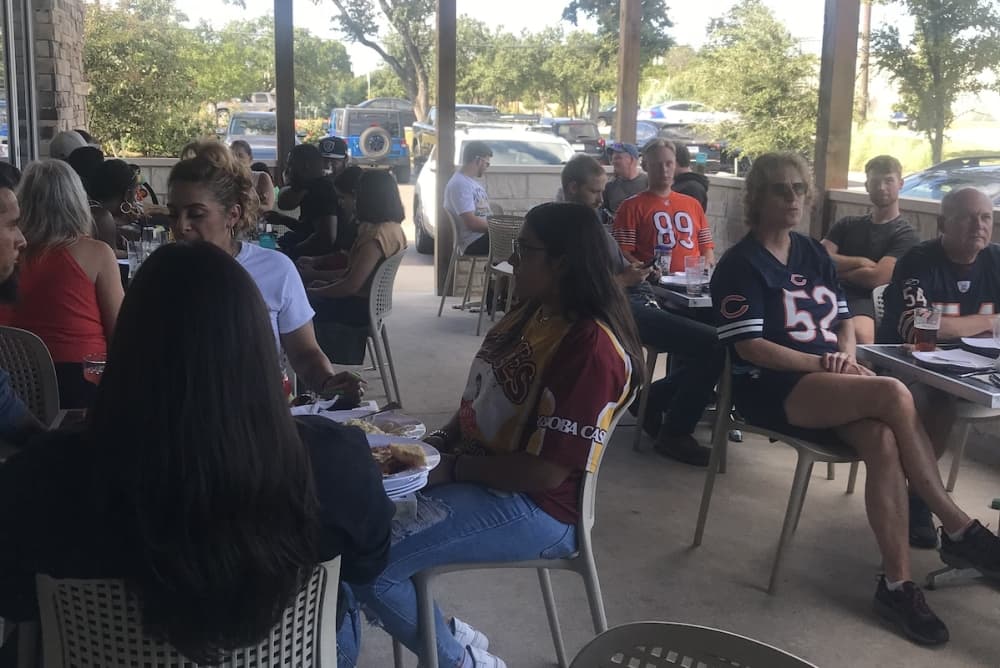 People gather outside on the patio to eat and watch football