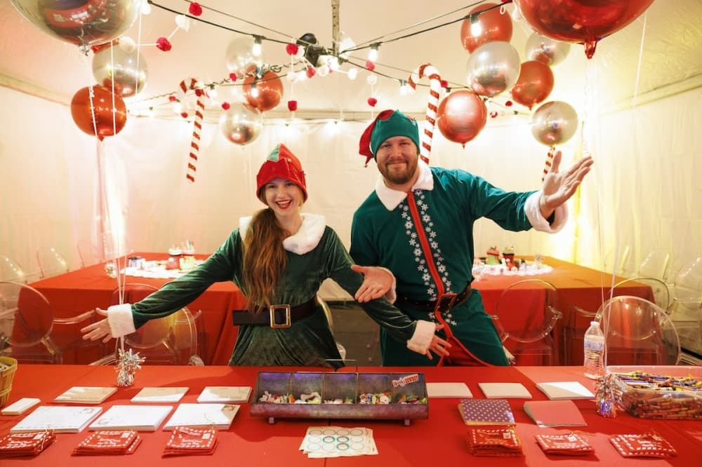 Two people dressed as Santa's elves at booth