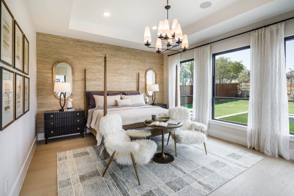 A photo of a bedroom with a bed, a bedside table, two chairs and a small table.