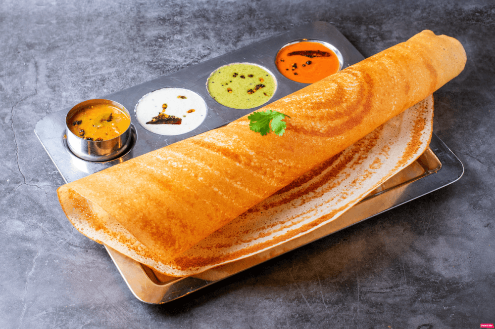 A plain dosa is on a table served with four different chutneys.