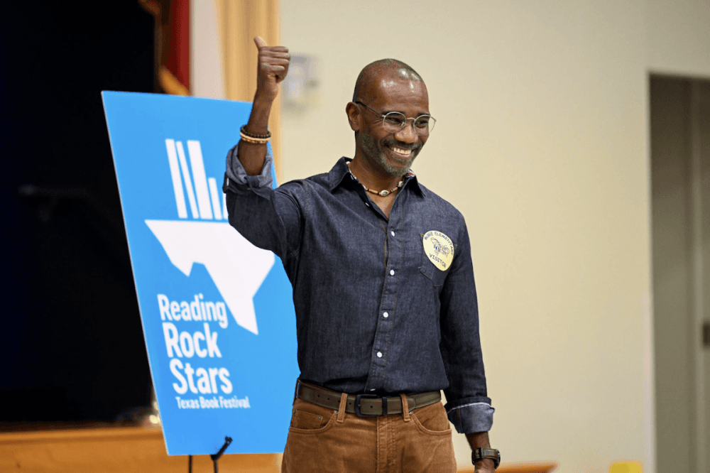A man smiling and standing in front of a blue Reading Rock Stars sign.