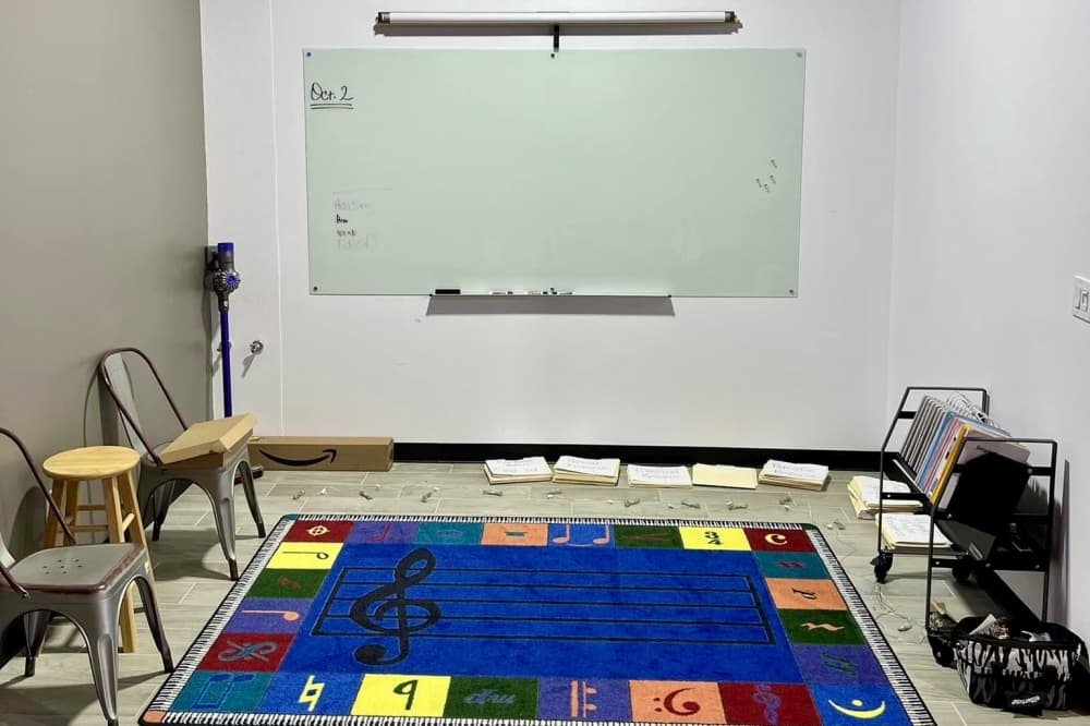 Room with white board, chairs, and a colorful rug for kids