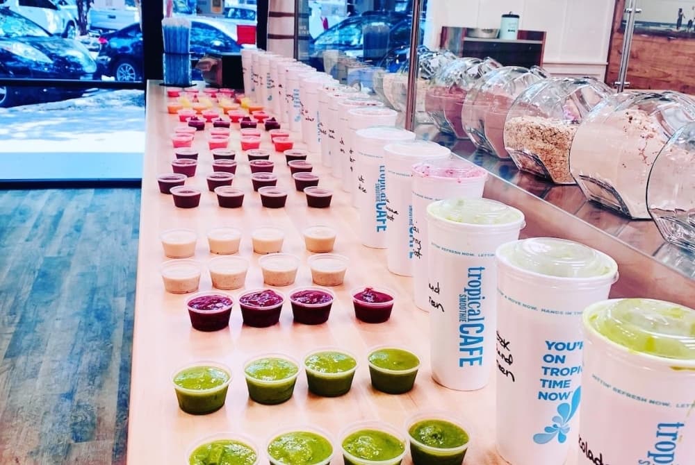 A row of colorful smoothie shots are placed on a bar inside the Tropical Smoothie location.