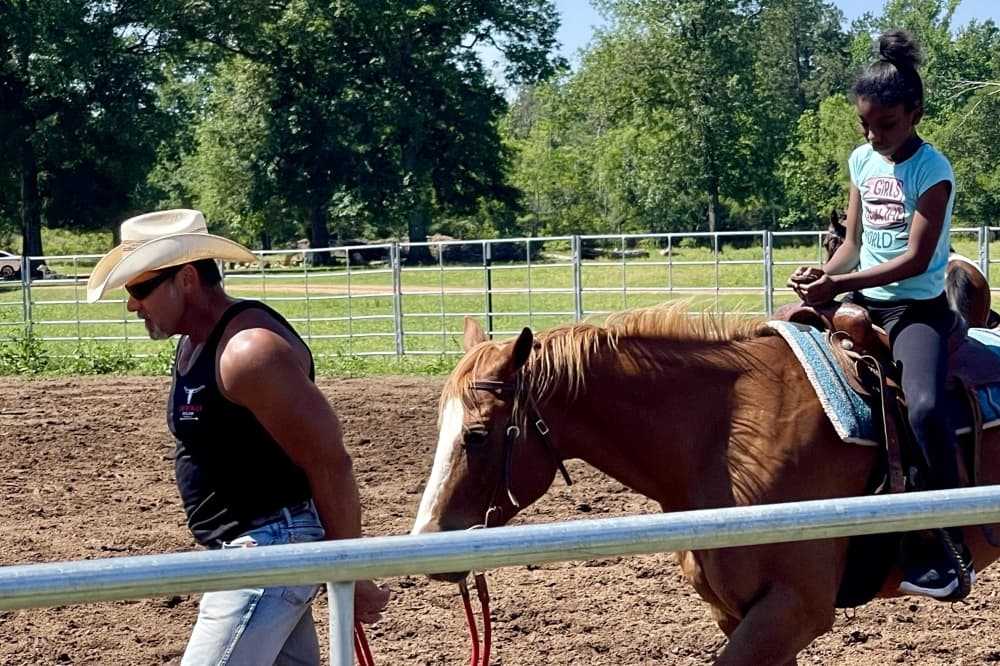 man guiding horse with girl on top of horse
