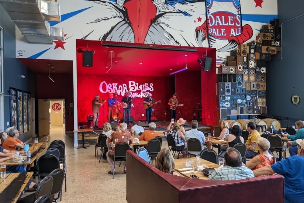 A group of people gather inside the venue to see the live performance on the stage.