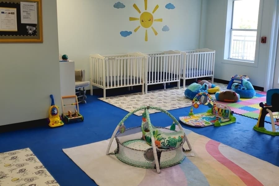 a room with three cribs and toys for toddlers