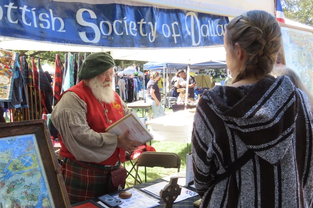 Member of Scottish Society of Dallas talks with guest at Plano International Festival. 
