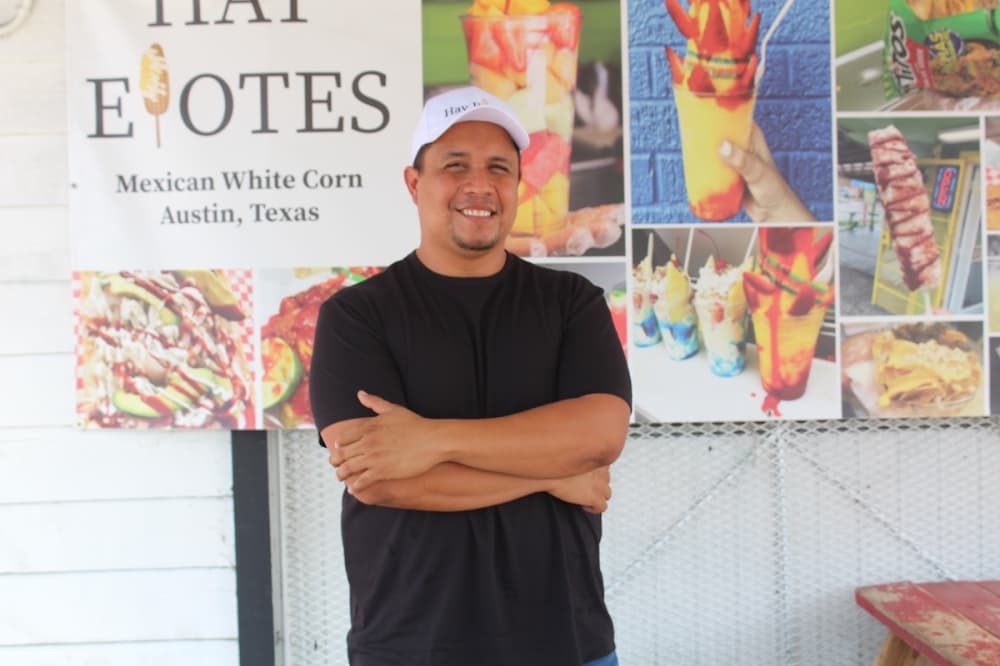 Jose Luis Cardona standing in front of a sign for his business 