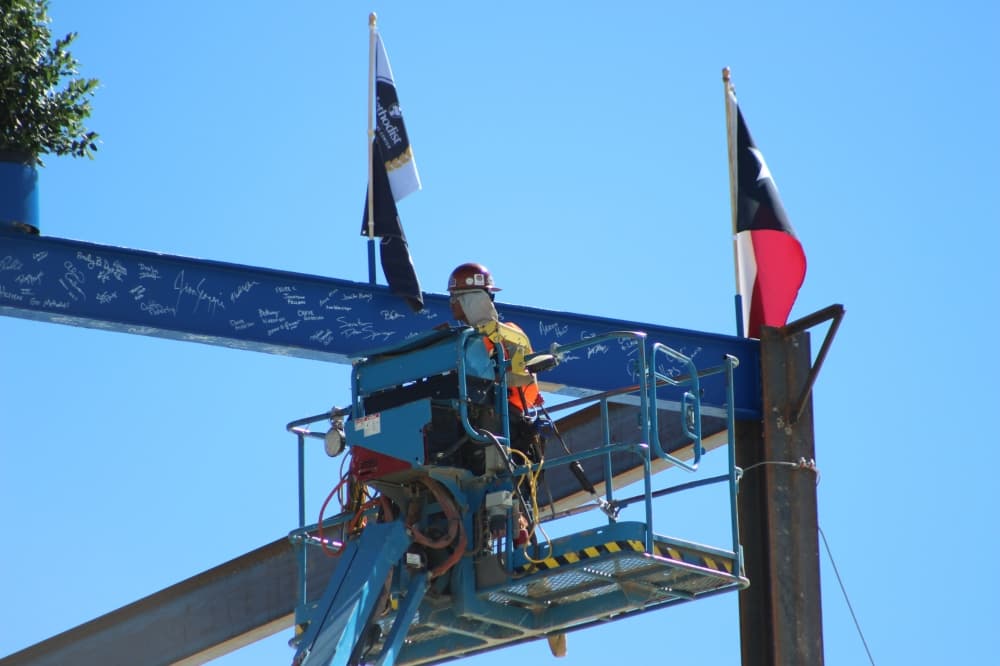 construction worker checking a beam at top of building